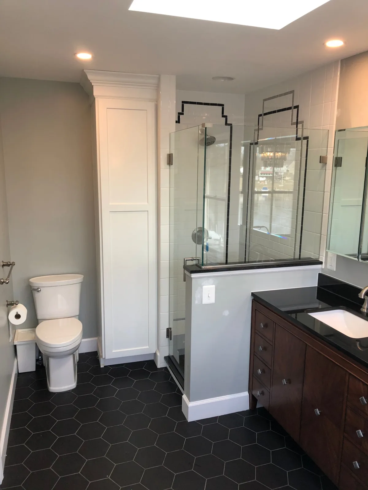 Completed bathroom remodel with black hex tile floor, glass shower, and art-deco tile accents by PRG Home Improvement in Maryland