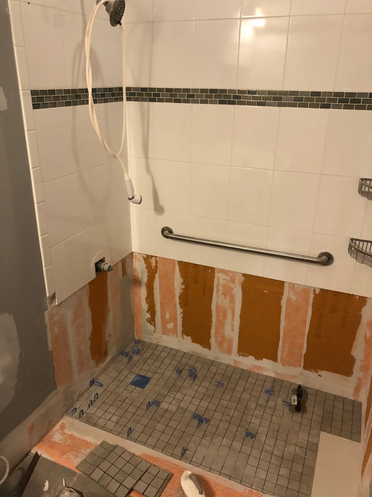 Shower remodel in progress with Schluter KERDI waterproofing membrane visible behind new tile