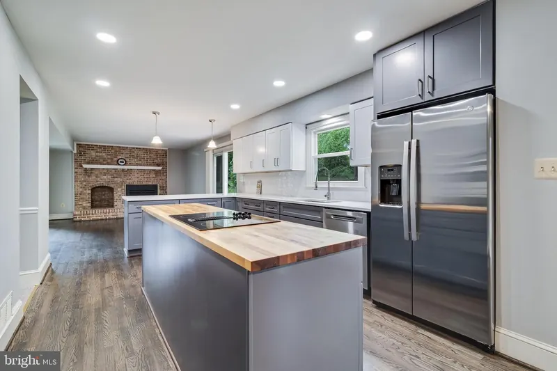 Open-concept kitchen remodel by PRG Home Improvement with gray cabinets, a butcher-block island, and stainless steel appliances