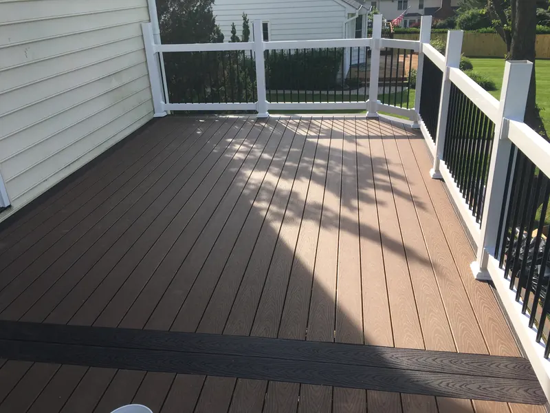 Two-tone composite deck surface with white vinyl railing and dark border inlay in Ellicott City MD
