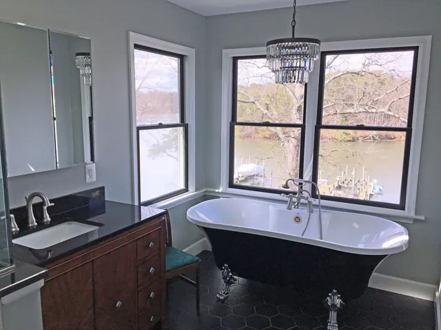 Black clawfoot soaking tub with crystal chandelier and waterfront view after master bathroom remodel in Pasadena MD