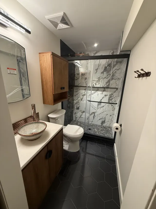 Completed designer bathroom with marble-look shower and copper vessel sink in Columbia MD